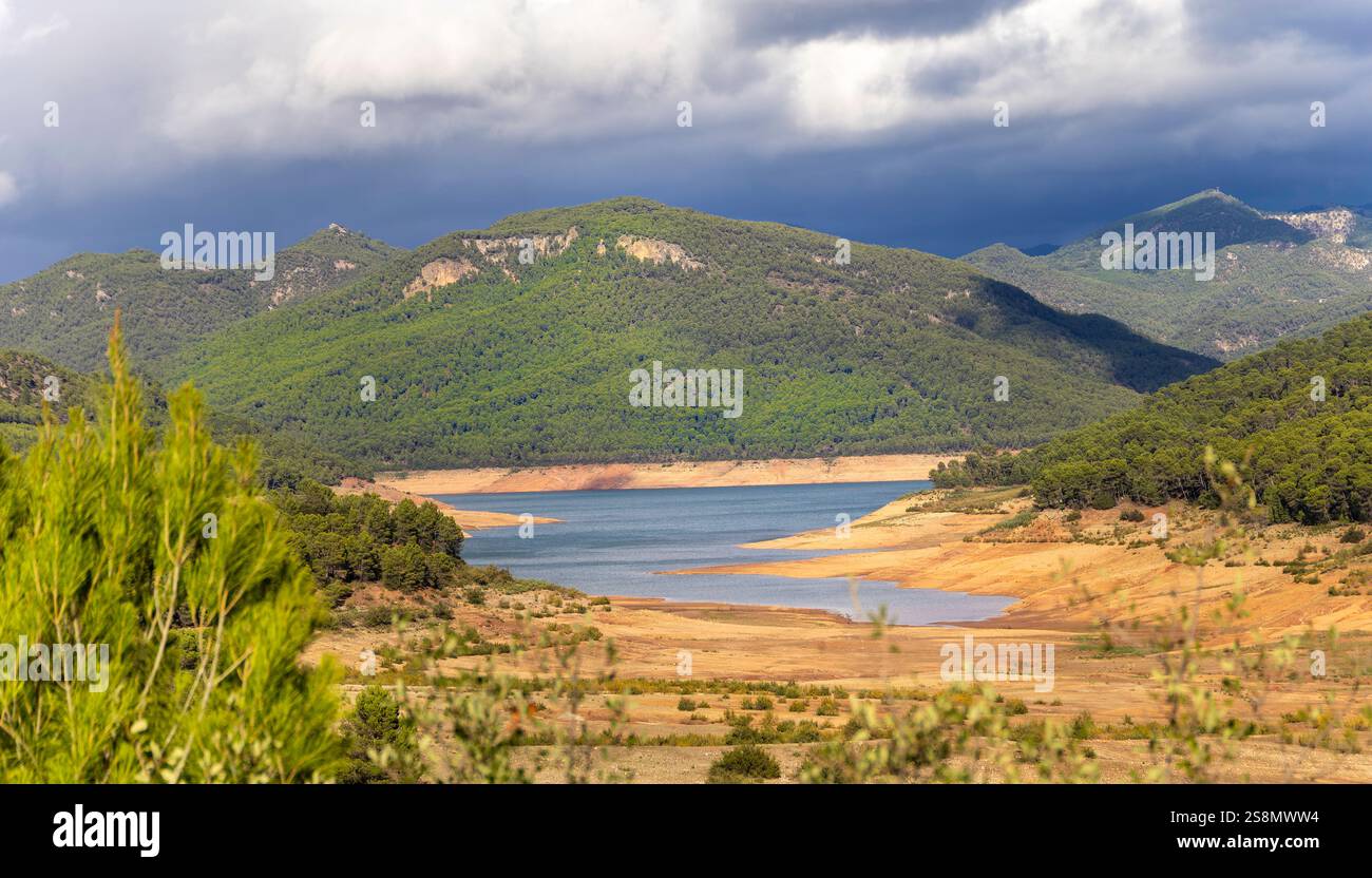 Eine wunderschöne Bergkette mit einem Fluss, der durch sie fließt. Der Himmel ist bewölkt und verleiht der Szene eine stimmungsvolle und ruhige Atmosphäre Stockfoto
