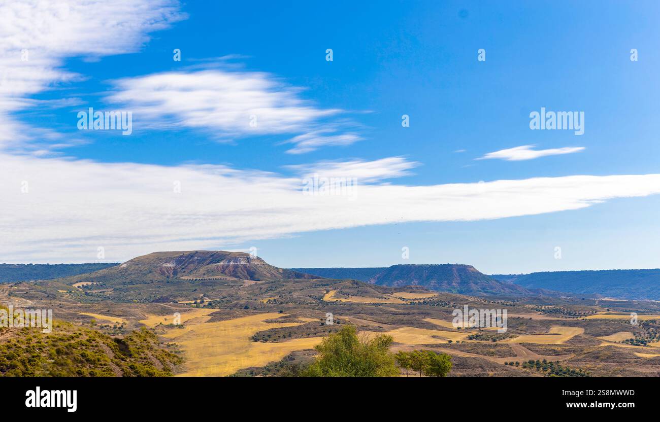 Landschaft erodierter Kalksteinhügel. Gelbes Gras und Gestrüpp sind im gesamten Gebiet verteilt. Der Himmel hat eine intensive blaue Farbe und einige Wolken. Stockfoto