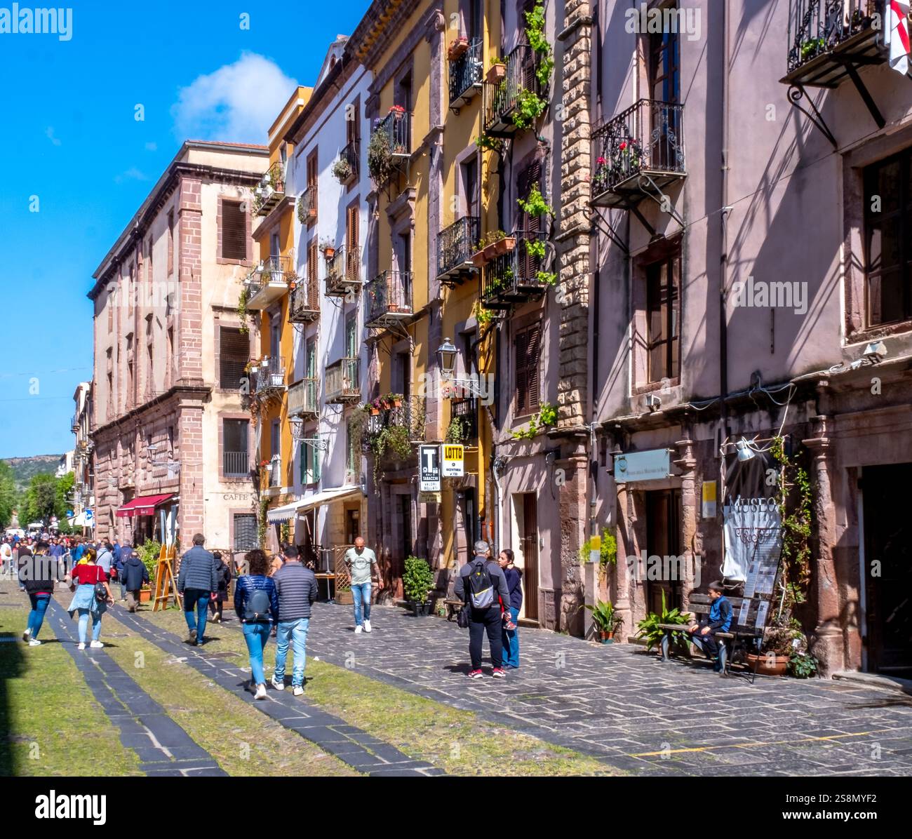 Touristen in einer Fußgängerzone, kunstvolle Balkone und Blumengestecke, Bosa, Europa, Provinz Oristano, Italien Stockfoto