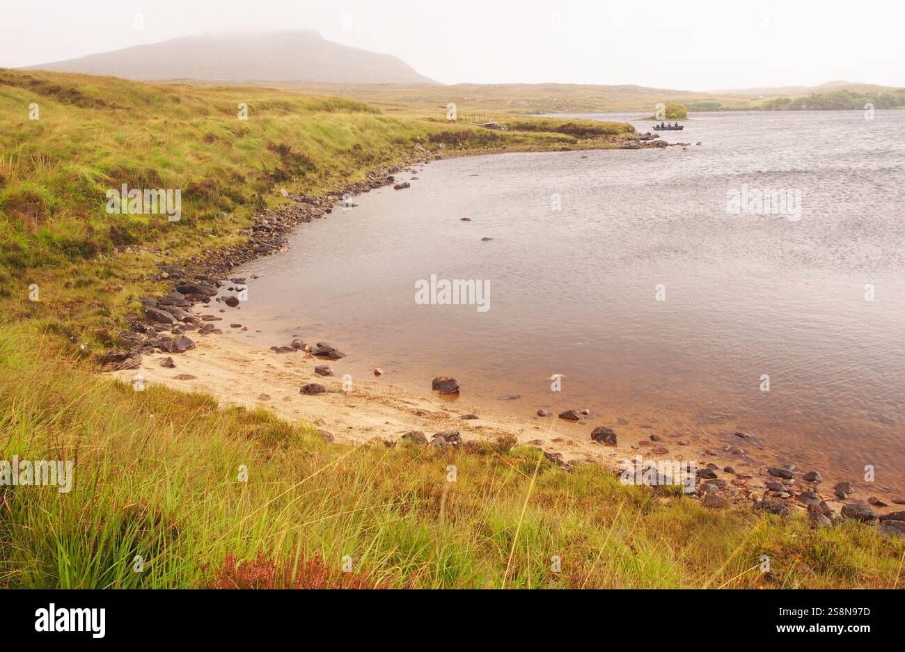 Leute fischen von einem kleinen Boot auf Loch Morsagail aus, das die düstere, zerklüftete Landschaft mit einem Berg im Hintergrund zeigt, Isle of Lewis, Schottland, Großbritannien Stockfoto