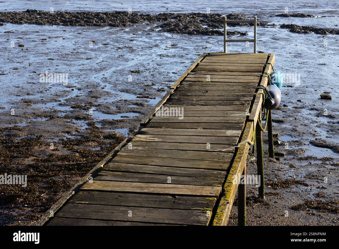 Ein zerbrechlicher, wackeliger, alter Gang, der zum Meer führt. Ebbe, schwimmt an der Seite der Struktur. Stockfoto