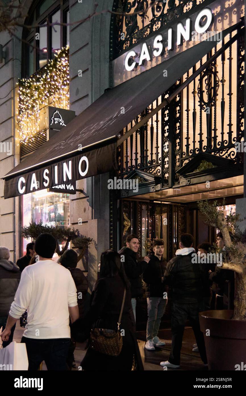 Madrid. Spanien - 23. Januar 2025: Nachtleben. Eine Gruppe von Menschen versammelt sich nachts vor einem hell beleuchteten Kasino-Eingang und zeigt das pulsierende Nachtleben Stockfoto