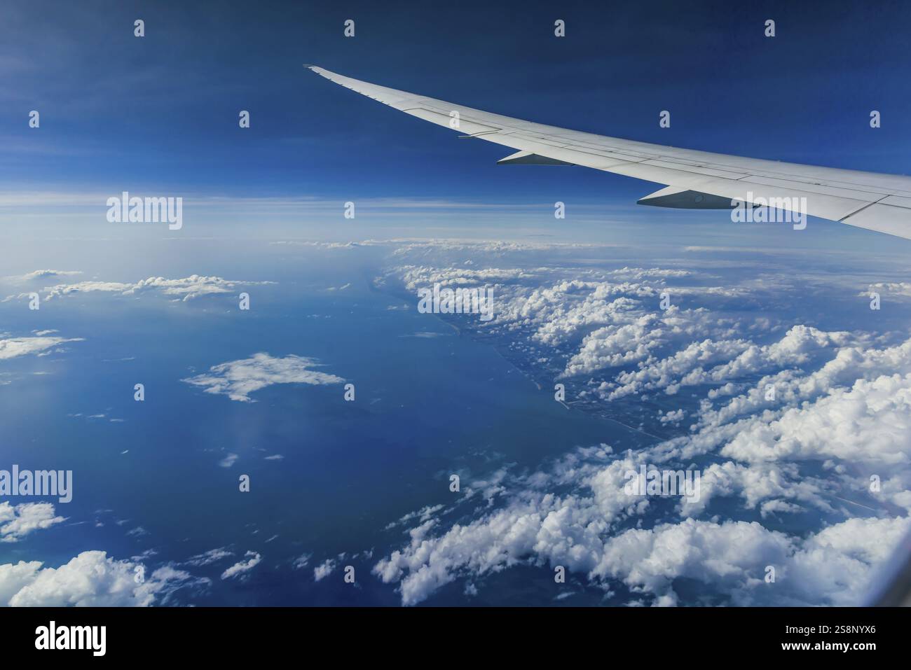 Über den Wolken über dem Indischen Ozean. Auf der linken Seite die Küste Indiens. Blick aus dem Flugzeugfenster während eines Fluges mit der Fluggesellschaft Etihad. Blau s Stockfoto