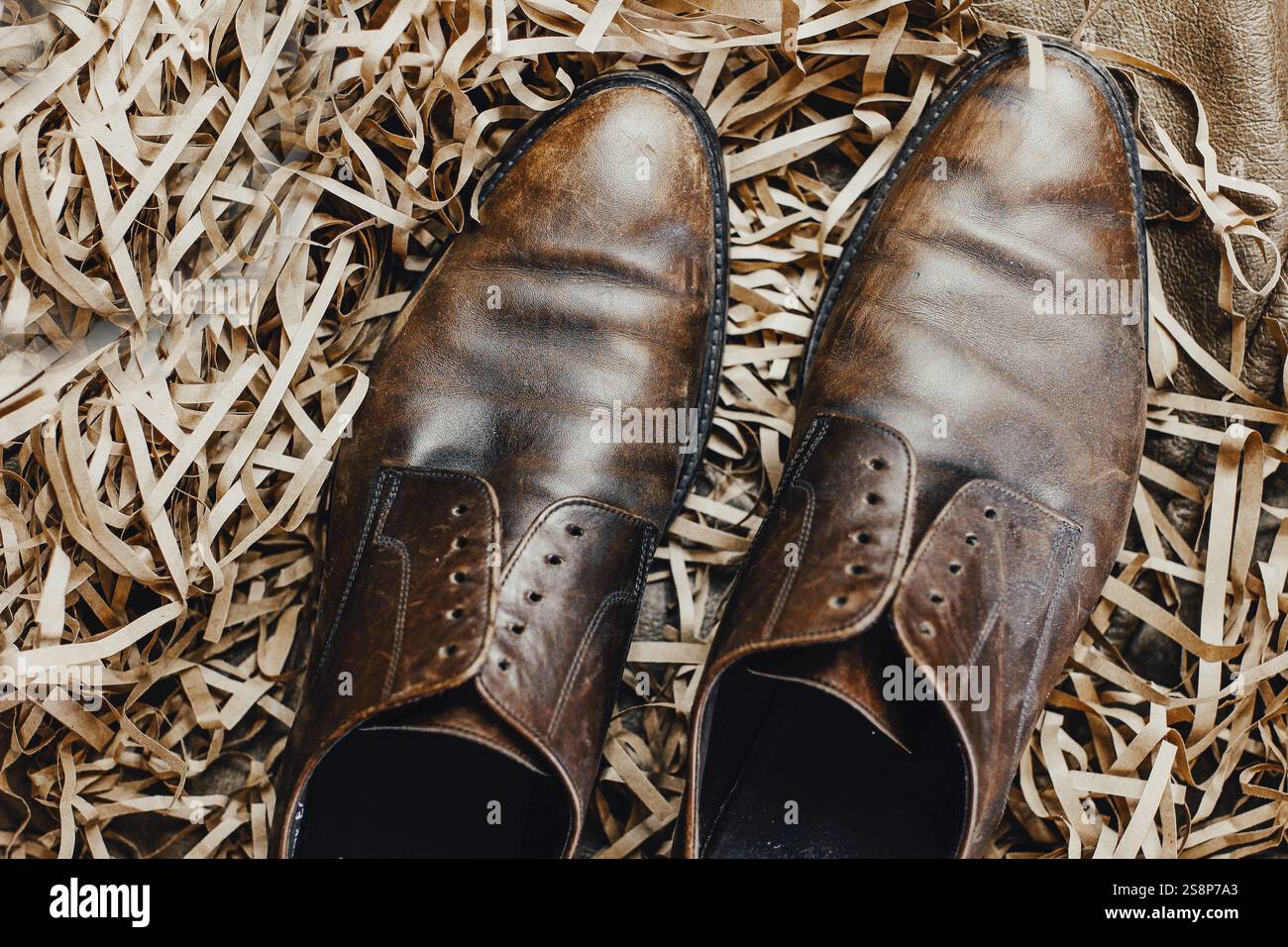 Lederschuhe auf Strohhalm für ein rustikales und erdiges Aussehen Stockfoto