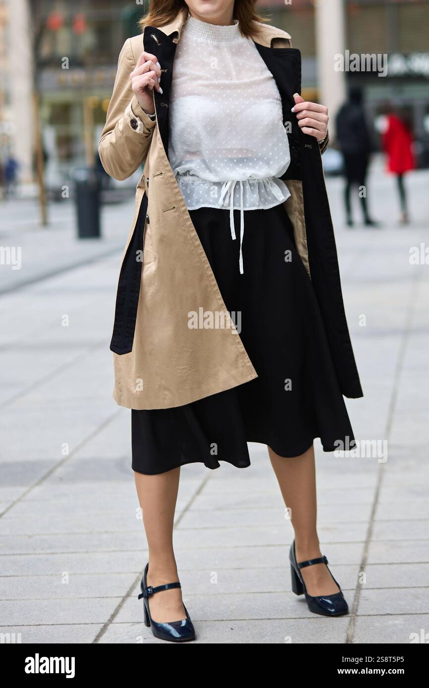Elegante Frau in Trenchcoat, schwarzem Rock, weißer Bluse, stilvollen Schuhen, urbanem Street-Style, City-Fashion-Konzept Stockfoto