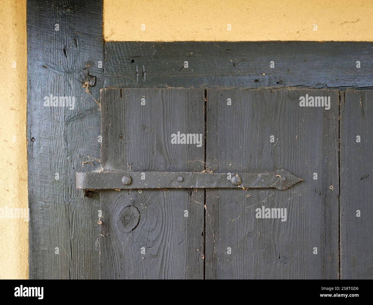 Türbeschläge für alte Schuppentüren im Fachwerk. Holztür in einer Fachwerkscheune. Die Türbeschläge mit der tiefen Holzmaserung. Stockfoto