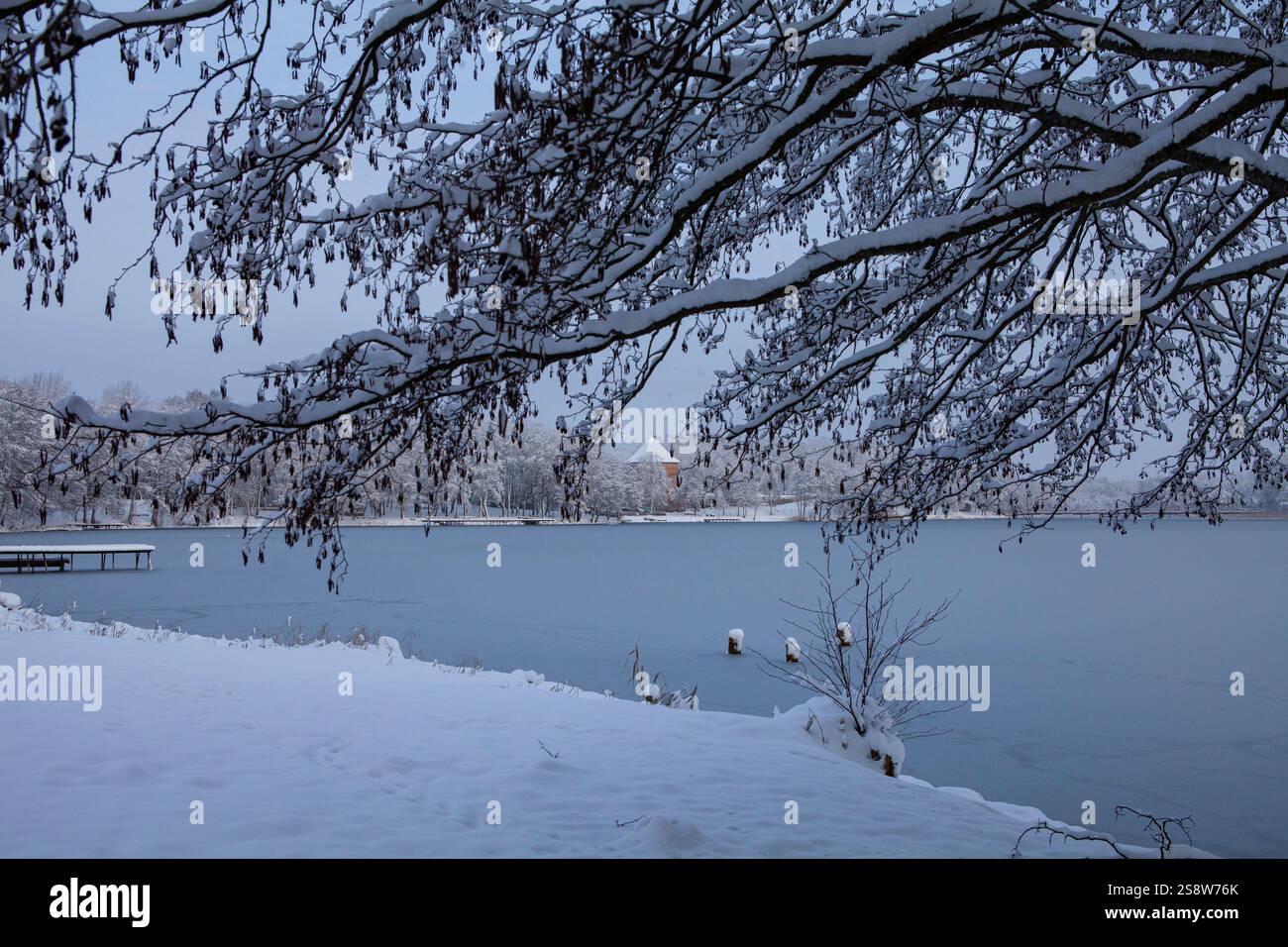 Die Schönheit eines Wintertages zeigt sich in diesem Bild des Bernardiner Sees in Trakai, Litauen. Die Sonne scheint hell über dem Kopf und wirft einen warmen Glo Stockfoto
