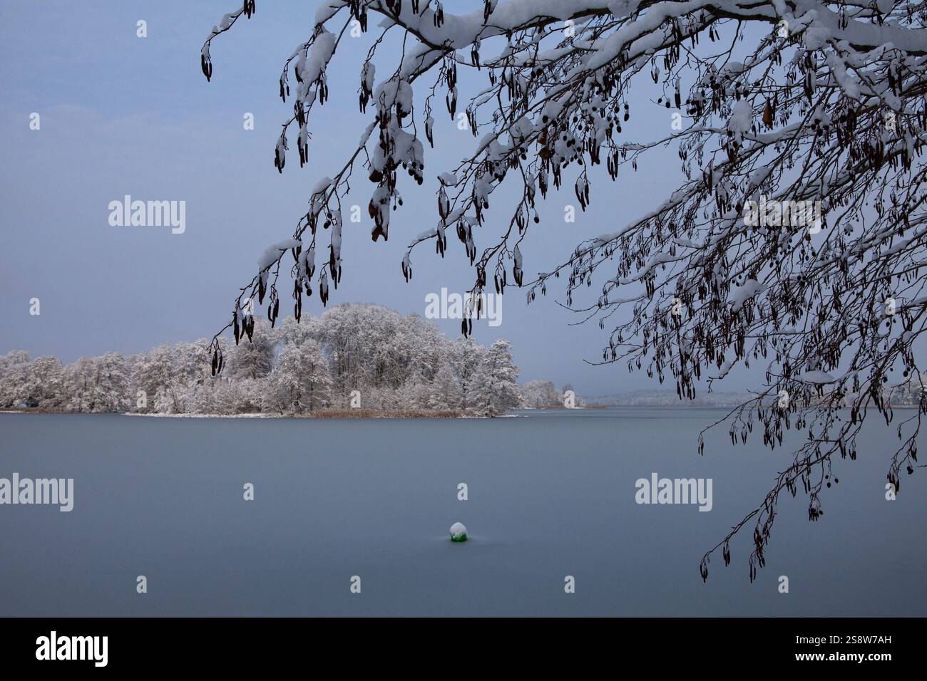 Die Schönheit eines Wintertages zeigt sich in diesem Bild des Galve-Sees in Trakai, Litauen. Die Sonne scheint hell über dem Himmel und strahlt ein warmes Leuchten aus Stockfoto