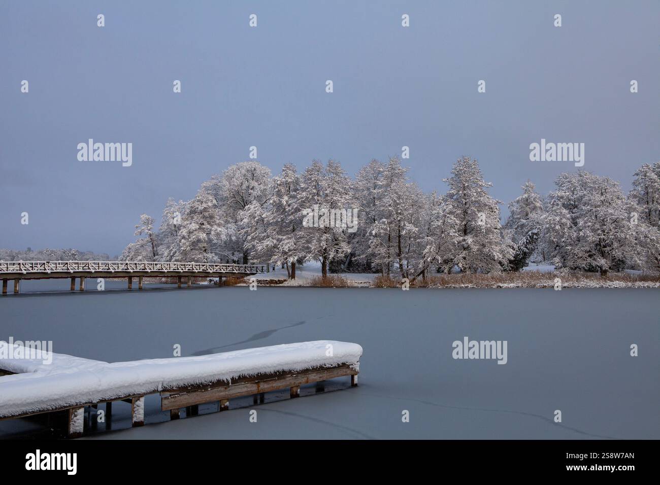 Die Schönheit eines Wintertages zeigt sich in diesem Bild des Galve-Sees in Trakai, Litauen. Die Sonne scheint hell über dem Himmel und strahlt ein warmes Leuchten aus Stockfoto