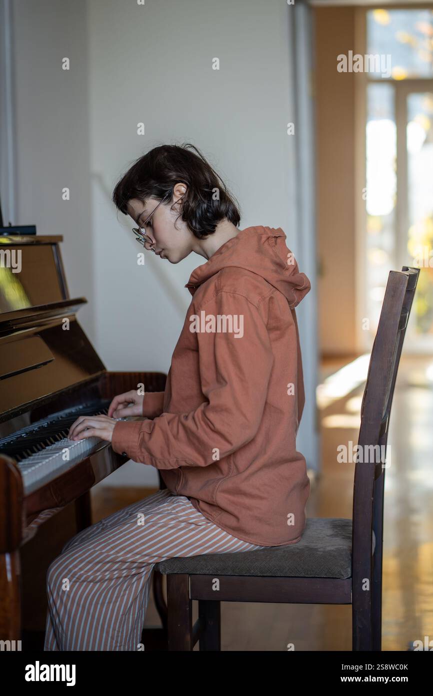 Konzentriert sich auf klassische Musik am Klavier, Pianistenmädchen-Tastentasten und das Üben von Fertigkeiten zu Hause Stockfoto
