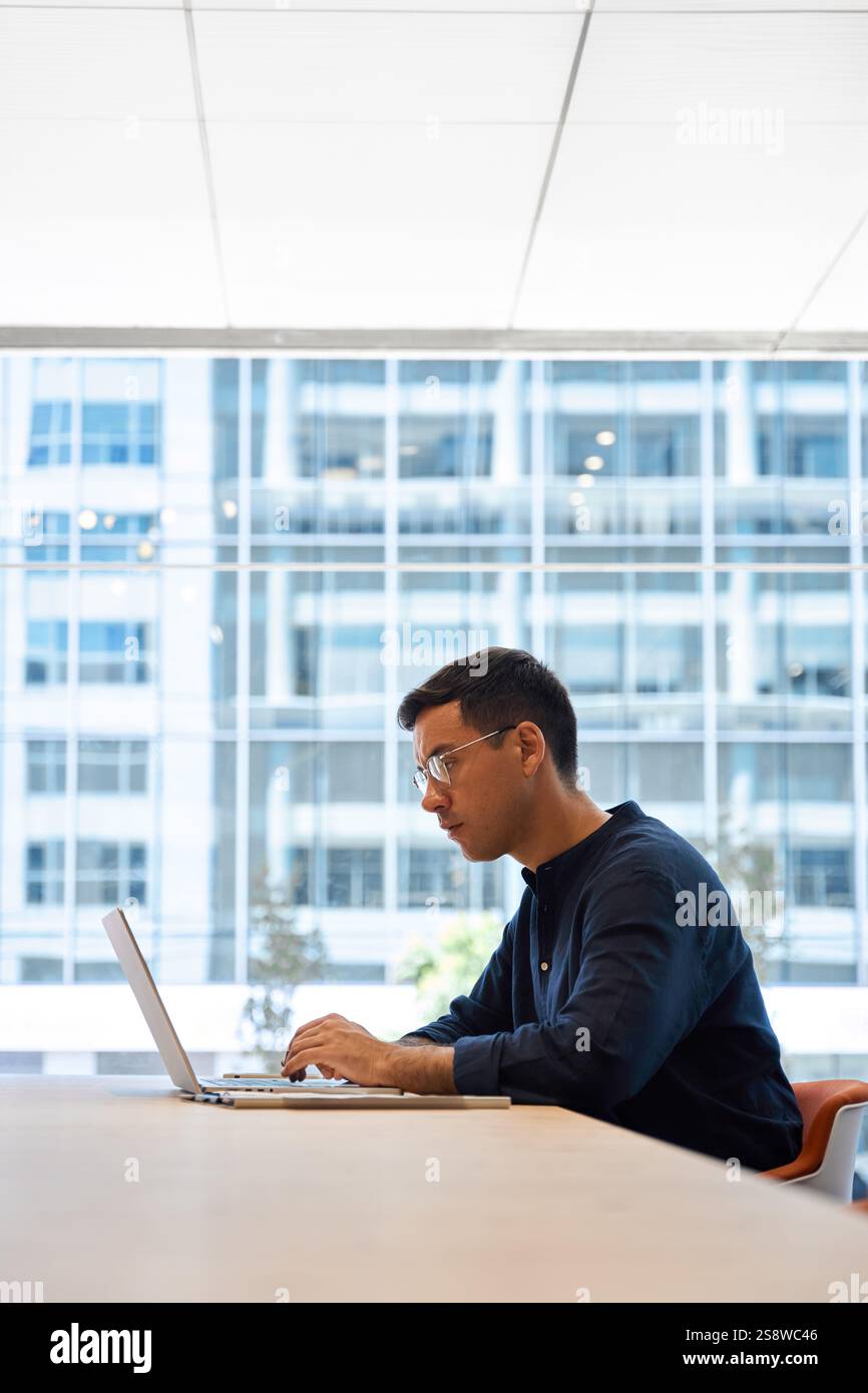 Ein geschäftiger Geschäftsmann, der einen Laptop benutzt und am Schreibtisch sitzt. Stockfoto