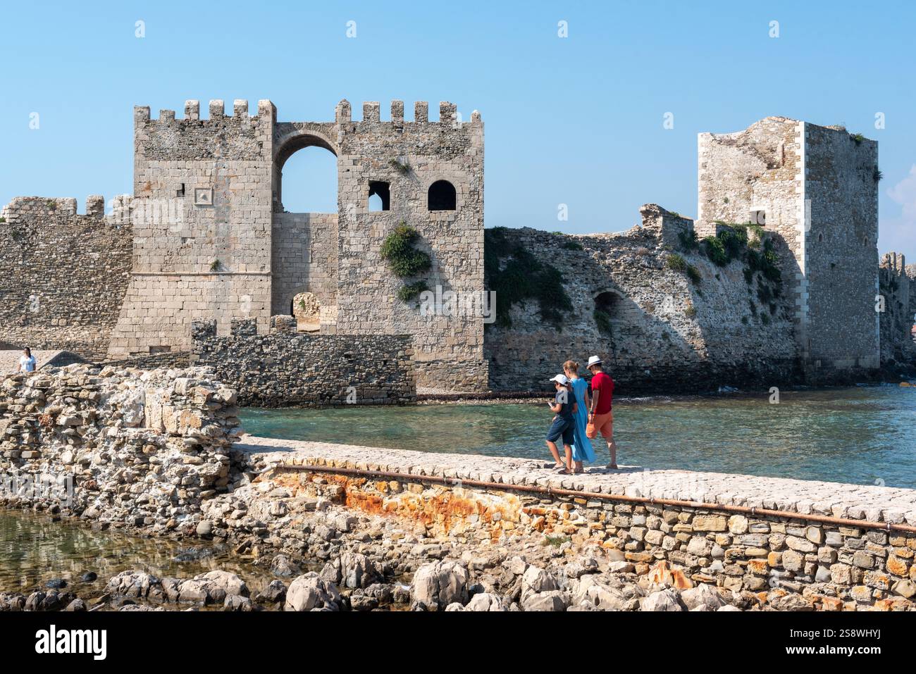 Eine Familie, die auf einer Steinbrücke im Schloss Methoni spaziert. Fassade des Schlosses. Alte Steinarchitektur. Griechenland. Stockfoto