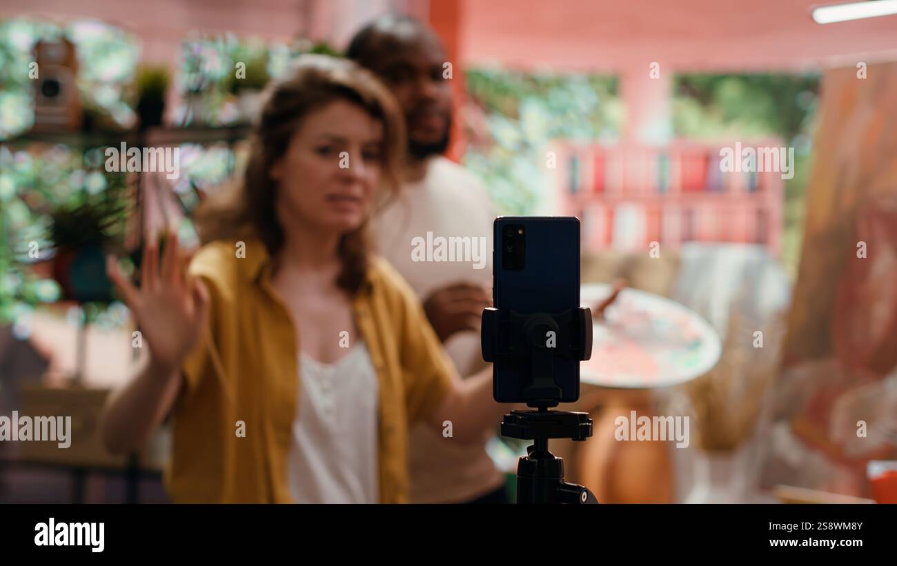 Frau Künstlerin moderiert Online-Kurs, um Produkte und Techniken zu präsentieren, die auf rustikalen Kunstwerken verwendet werden, und nimmt Tutorial online auf. Team von Malern, die Meisterklasse für E-Learning, Kunstunterricht machen. Kamera A.. Stockfoto