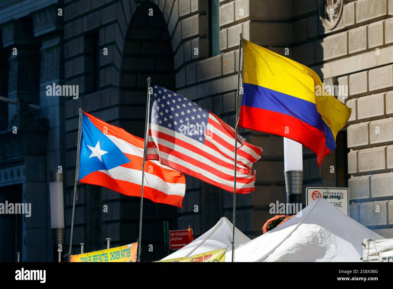 Die Flaggen von Puerto Rico, den Vereinigten Staaten und Kolumbien fliegen Seite an Seite auf einer Straßenmesse in Manhattan Stockfoto