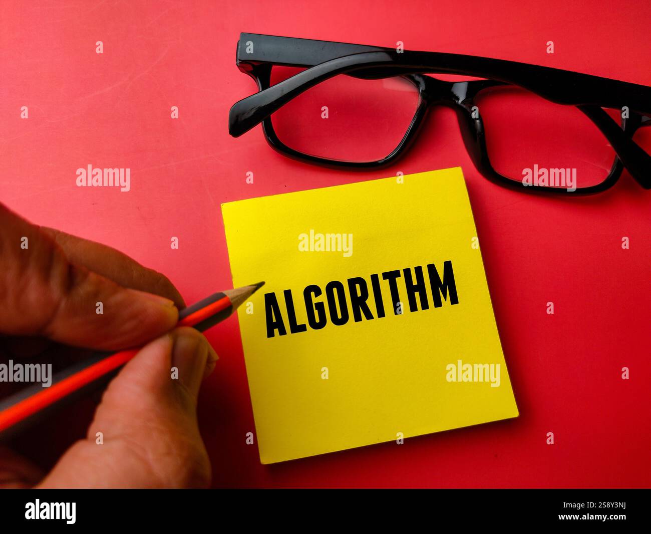 Hand hält Bleistift und Haftnotiz mit TEXTALGORITHMUS auf rotem Hintergrund. Stockfoto