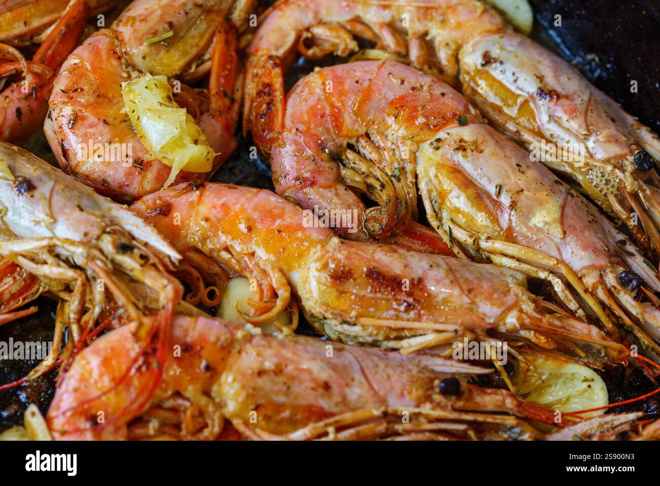 Langoustine in einer Pfanne mit Butter, Zitrone und Knoblauch. Gegrillte große Garnelen, in einer Pfanne gekochte Langusten mit Gewürzen, Kräutern und Zitrone. Stockfoto