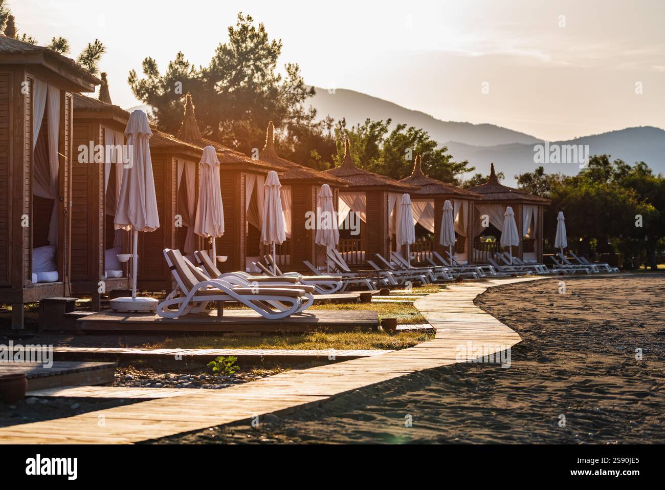 Private Strandhütten an einer ruhigen Sandküste bei Sonnenuntergang Stockfoto