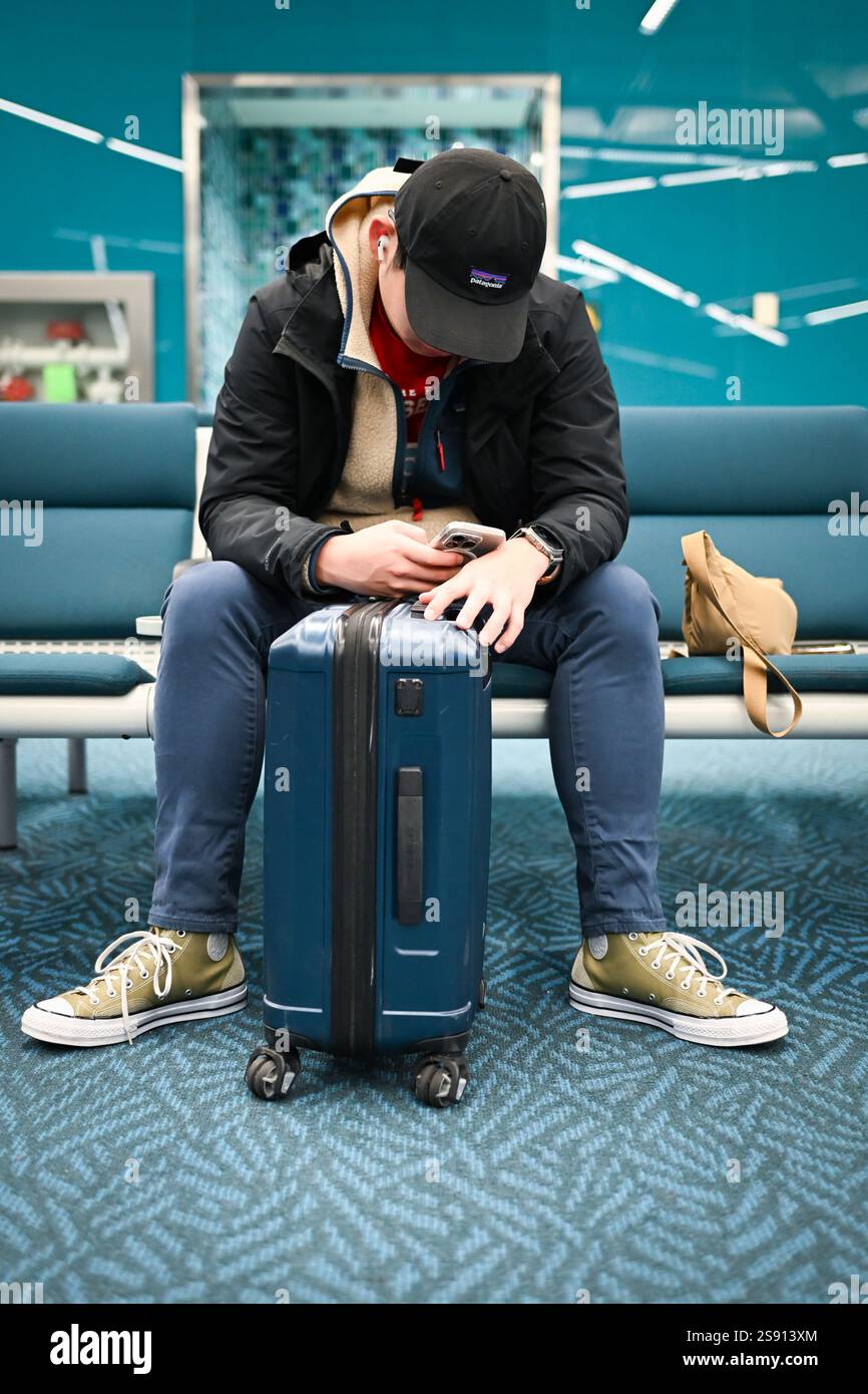 Der Mann wartet auf das Flugzeug, während er telefoniert Stockfoto