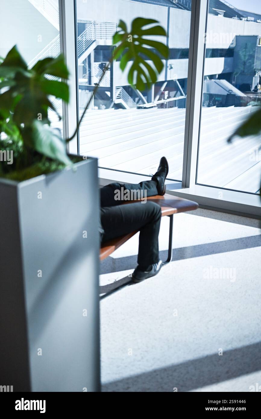 Flughafen-Lounging in der Nähe von Pflanzen Fuß sichtbare mittlere Reichweite Stockfoto