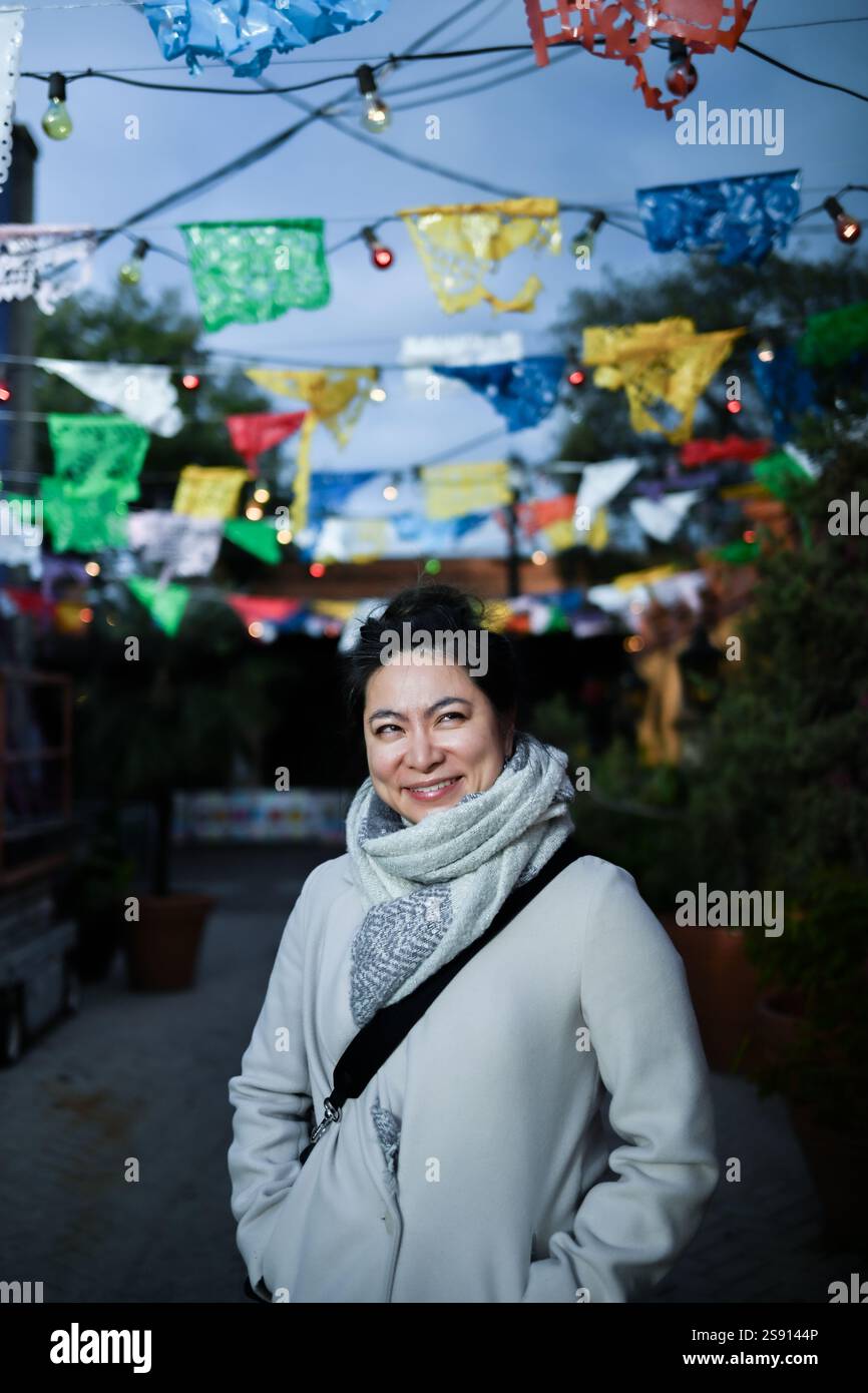 Asiatische Frau steht in Nahaufnahme unter farbigem Papier Stockfoto
