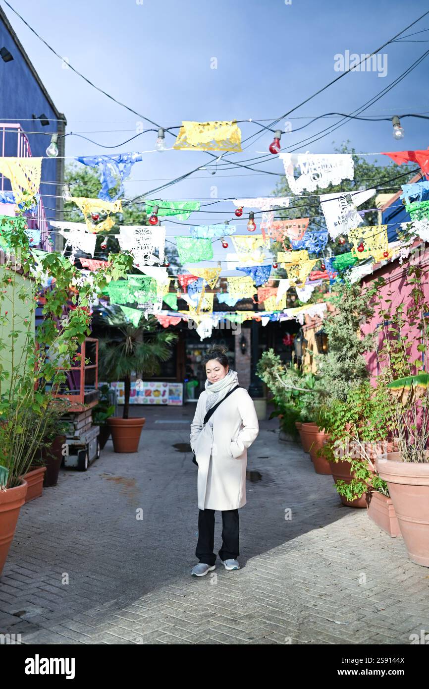Asiatische Frau steht unter farbigem Papier auf dem Markt von San Antonio Stockfoto