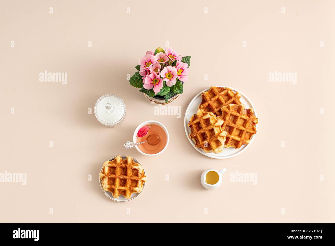 Waffeln und Tee mit Blumen in weichen Beigetönen Stockfoto