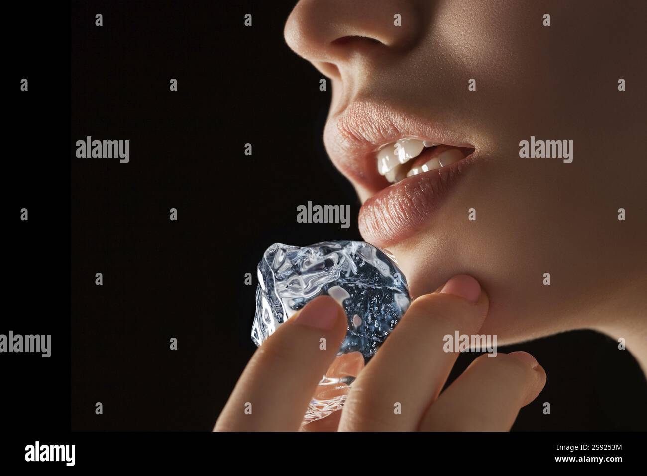 Ein Foto eines Eiswürfels in den Fingern und auf dem Weg zu den Lippen Stockfoto