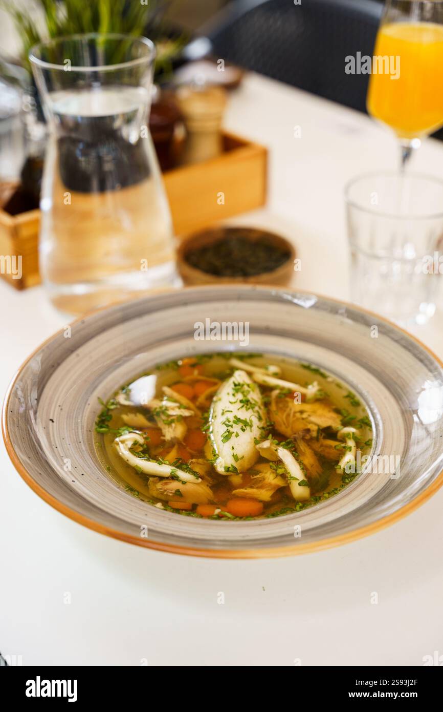 Ein perfekt gegrilltes Lachsfilet, serviert mit geröstetem Gemüse und einer cremigen Sauce auf einem dekorativen Teller. Das Gericht wird mit Spinatblättern garniert. Stockfoto