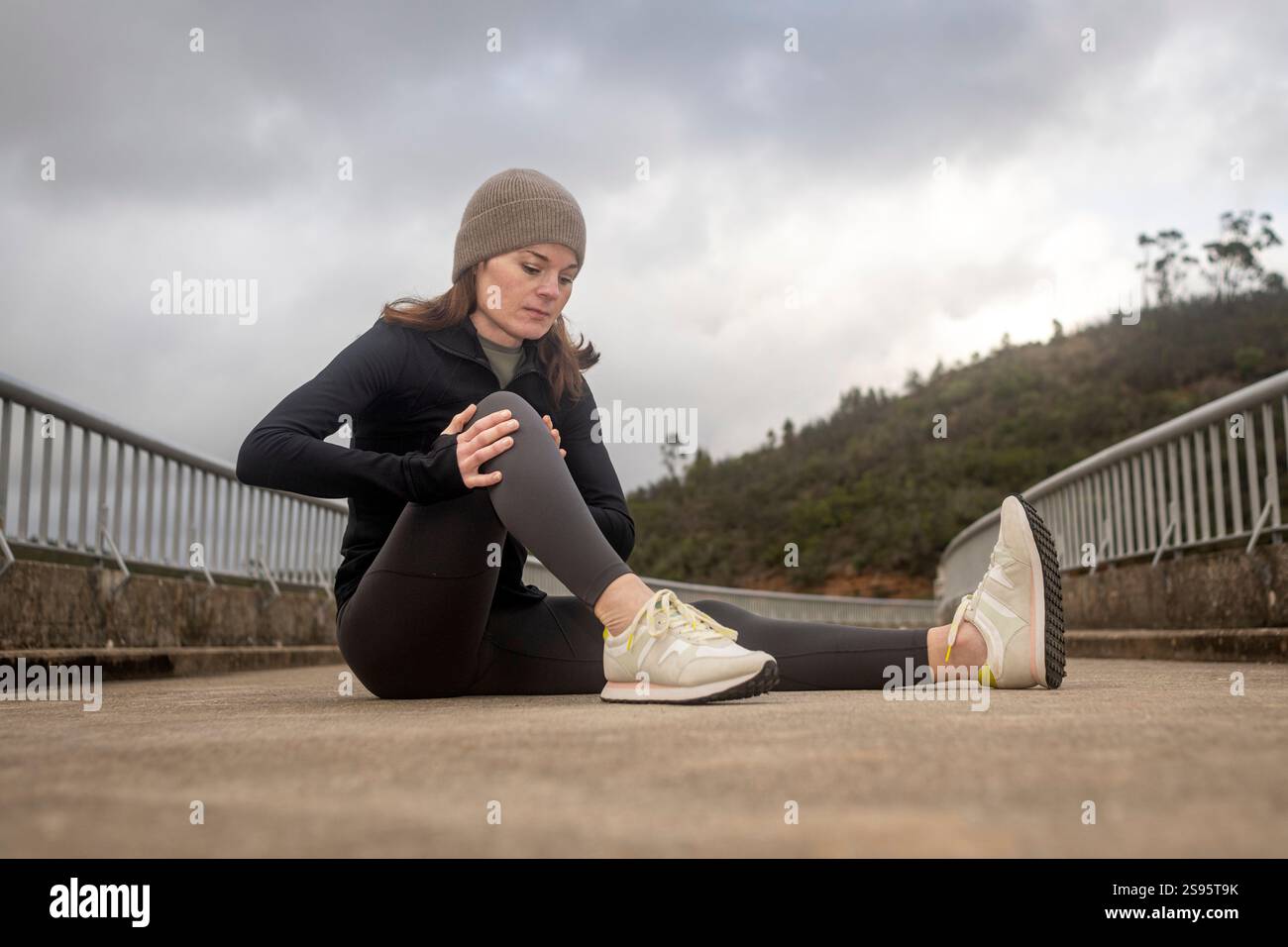 Joggerin, die ihr Knie auf der Straße hält Stockfoto