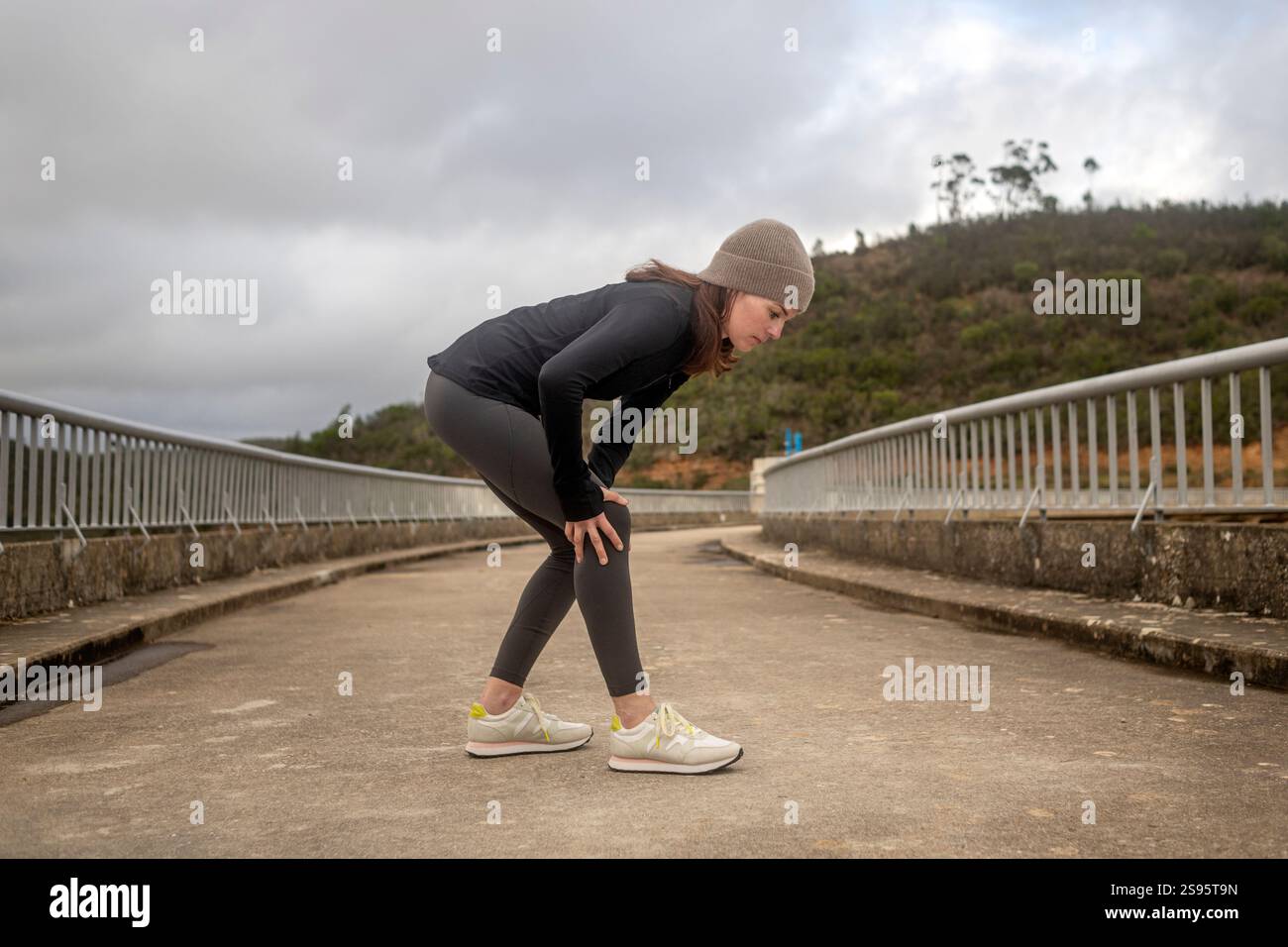 Joggerin, die ihr Knie schmerzhaft hält Stockfoto