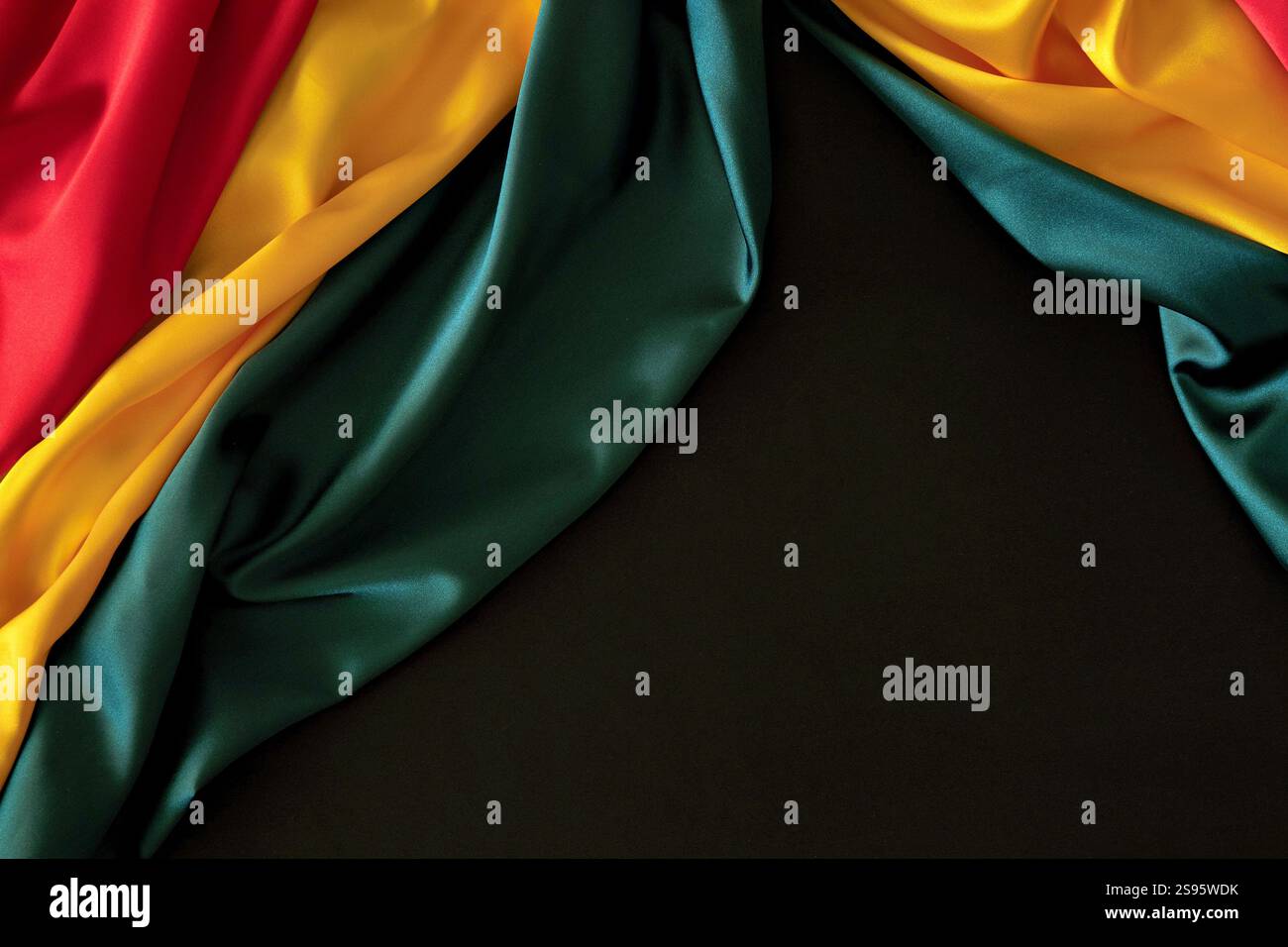 Hintergrund für schwarzen Monat. Rote, gelbe, grüne Farben Vorhänge, Seidenfahne auf schwarzem Hintergrund. Draufsicht Stockfoto
