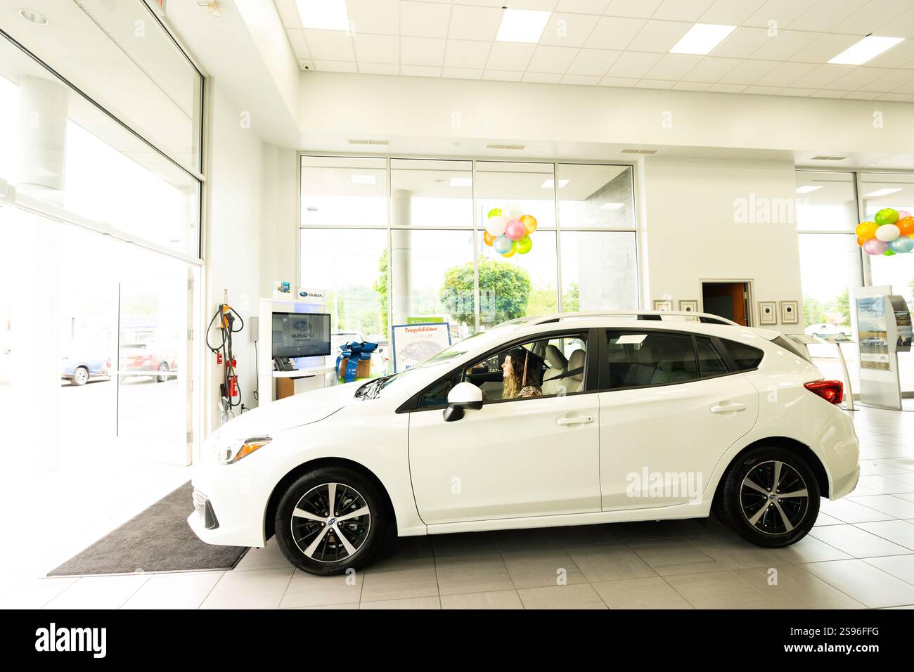Eine Studentin kauft ein nagelneues Auto und fährt es aus der Ausstellungsgarage in Kentucky, USA Stockfoto