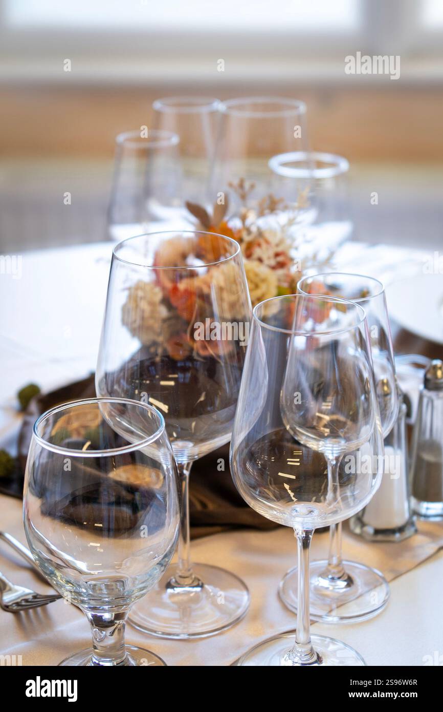 Ein elegant gestalteter Tisch mit mehreren Weingläsern, Salz- und Pfefferstreuern und einem dekorativen Blumenaufsatz. Stockfoto