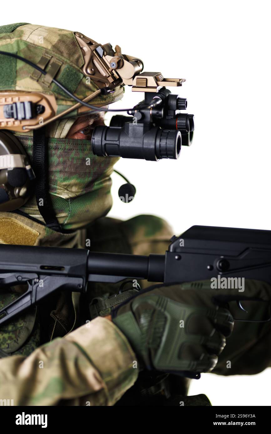 Ein Soldat in taktischer Militärausrüstung und Tarnuniform, der eine Waffe hält und eine Nachtsichtbrille trägt Stockfoto