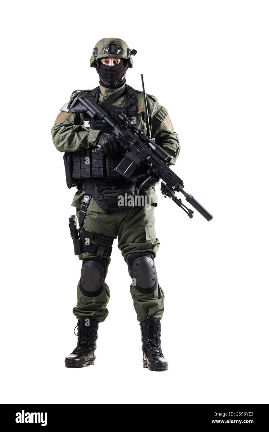 Ein Militäroffizier in voller taktischer Ausrüstung und Helm steht mit einem Sturmgewehr und zeigt in einem isolierten Studio seine Bereitschaft und Professionalität Stockfoto