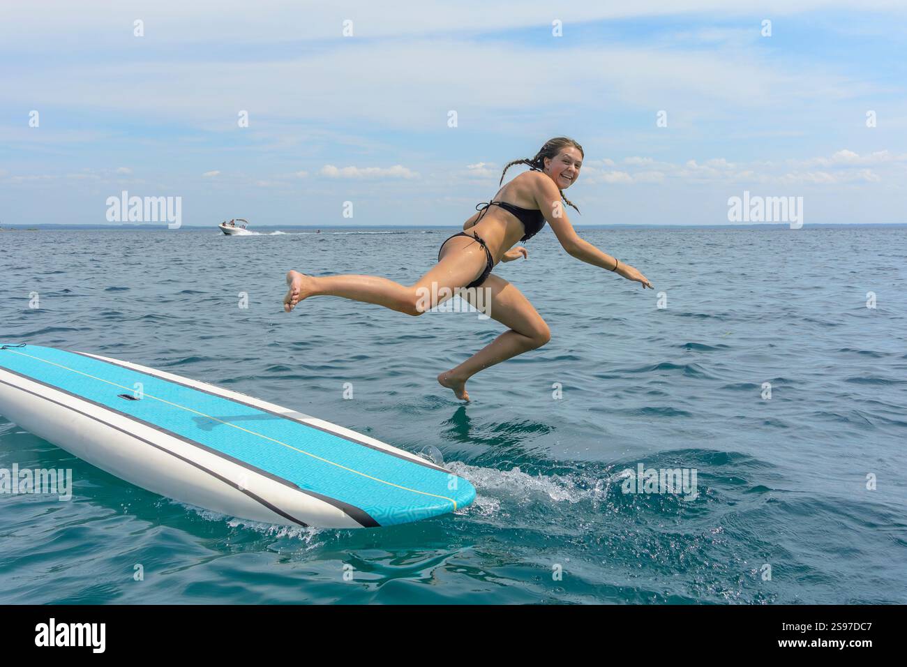 Junge Erwachsene Frau, die vom Paddelbrett springt Stockfoto