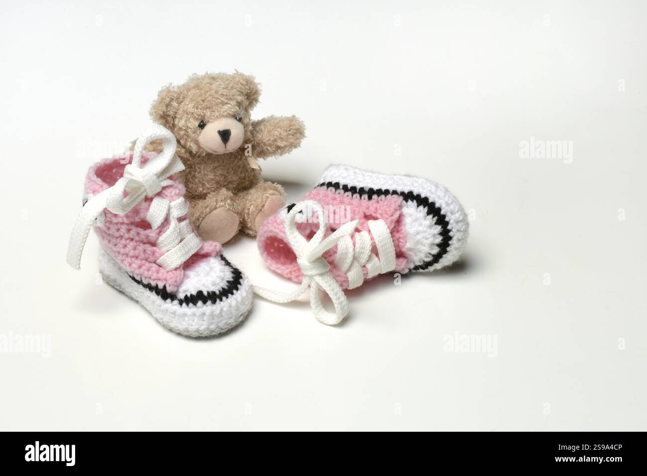 Babyschuhe und Teddybär, weißer Hintergrund Stockfoto