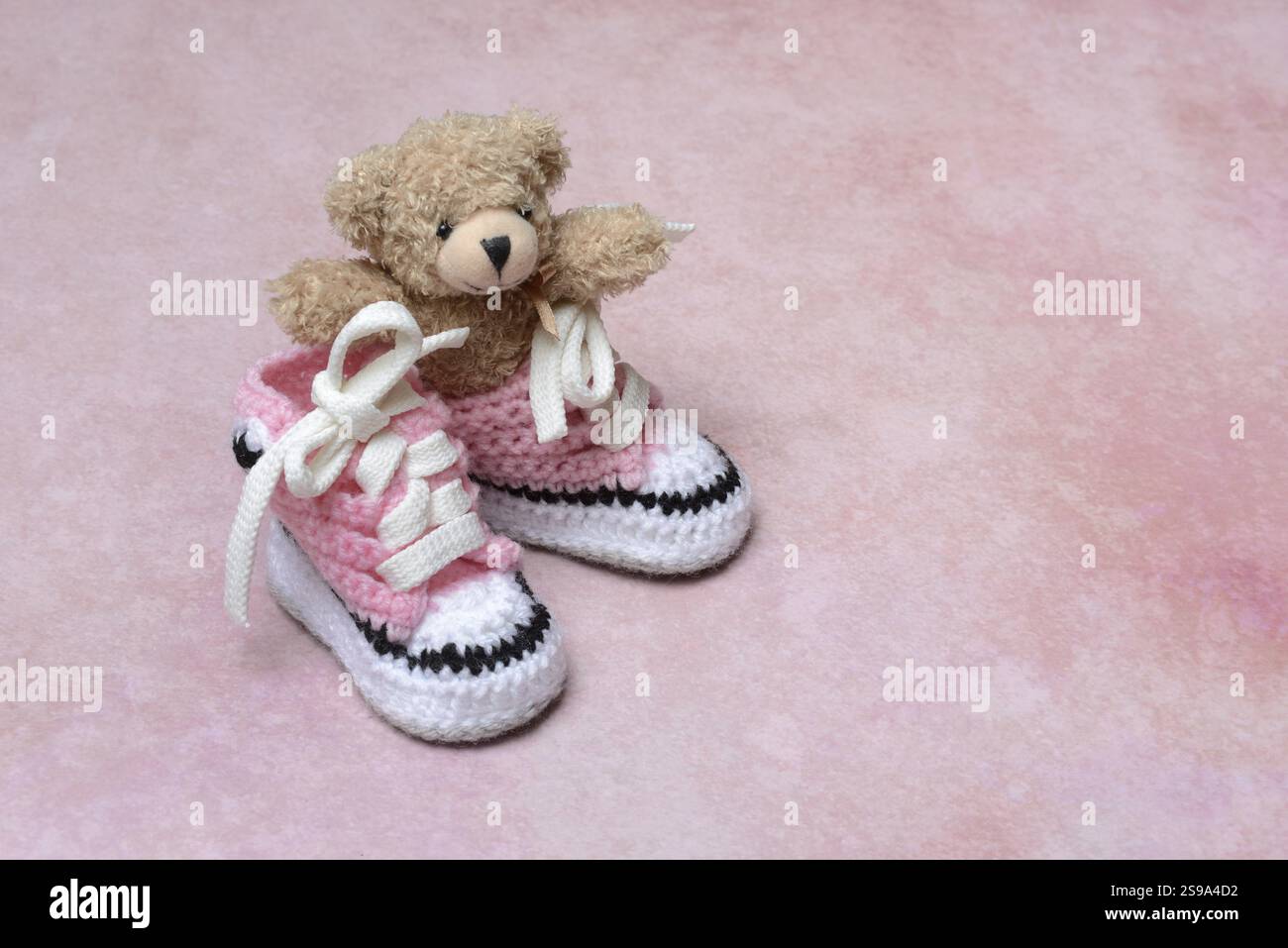 Babyschuhe und Teddybär mit rosa Hintergrund, handgefertigt Stockfoto