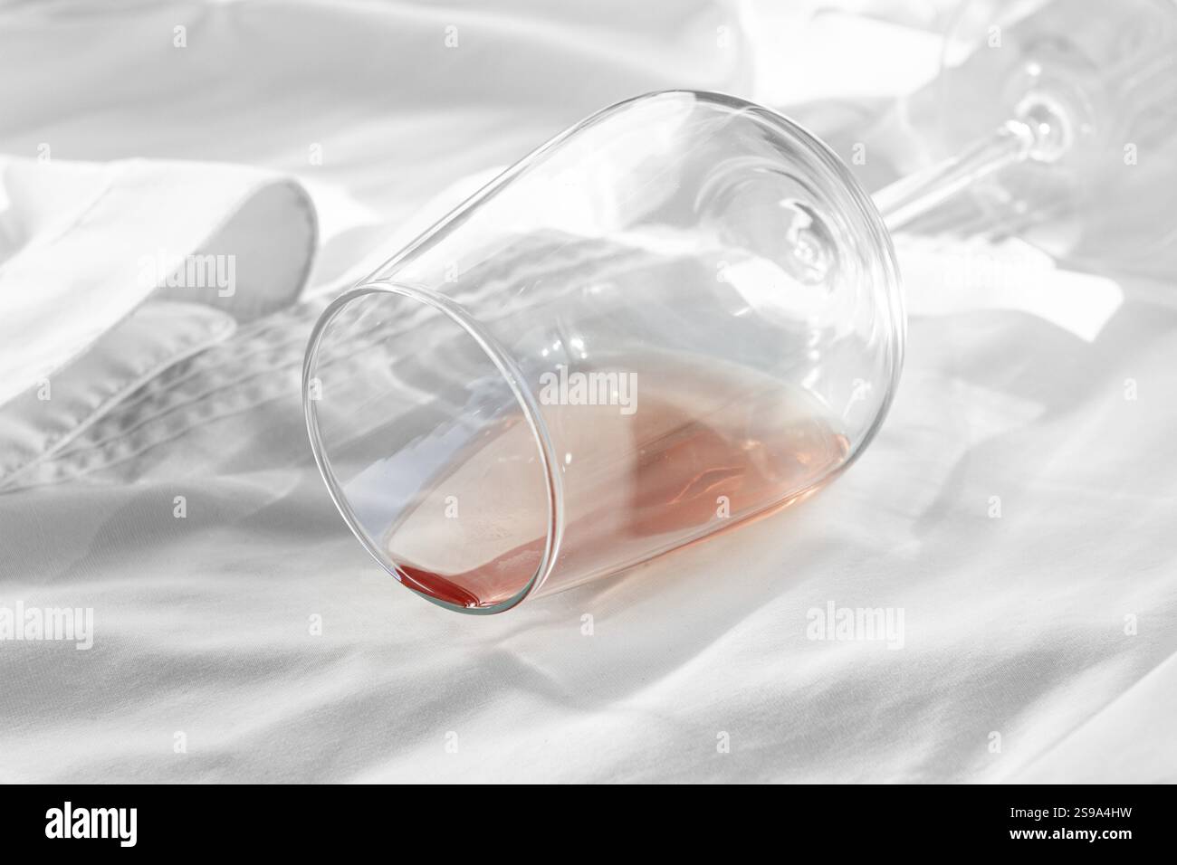 Glas, mit rosafarbenem Wein, verschüttet auf einem weißen Hemd, Nahaufnahme, selektiver Fokus, keine Leute, Konzept, Draufsicht Stockfoto
