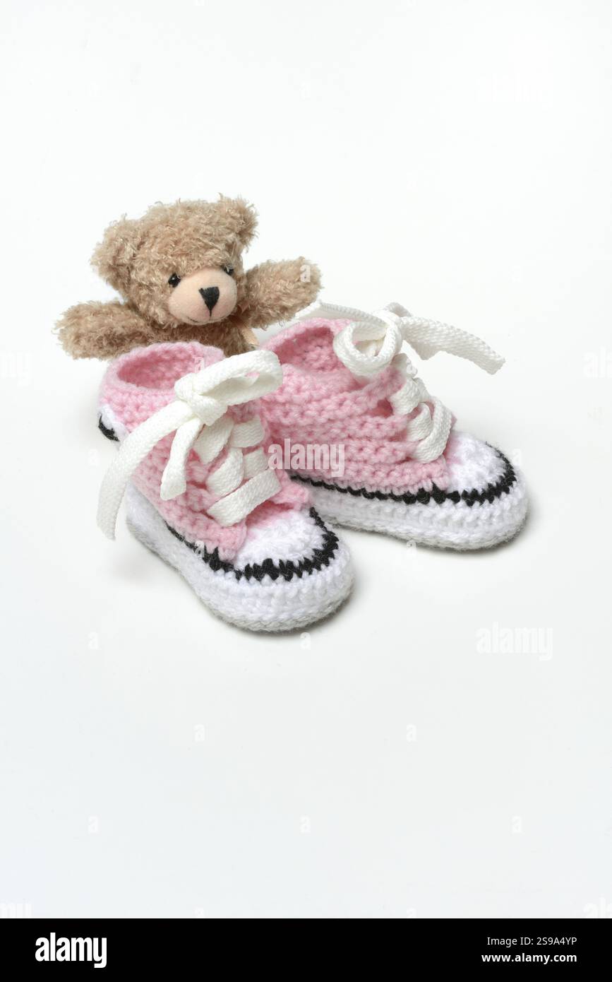 Babyschuhe und Teddybär, weißer Hintergrund Stockfoto