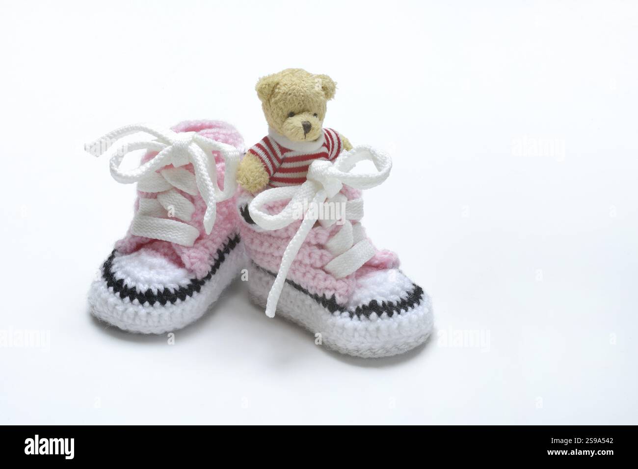 Babyschuhe und Teddybär, weißer Hintergrund Stockfoto