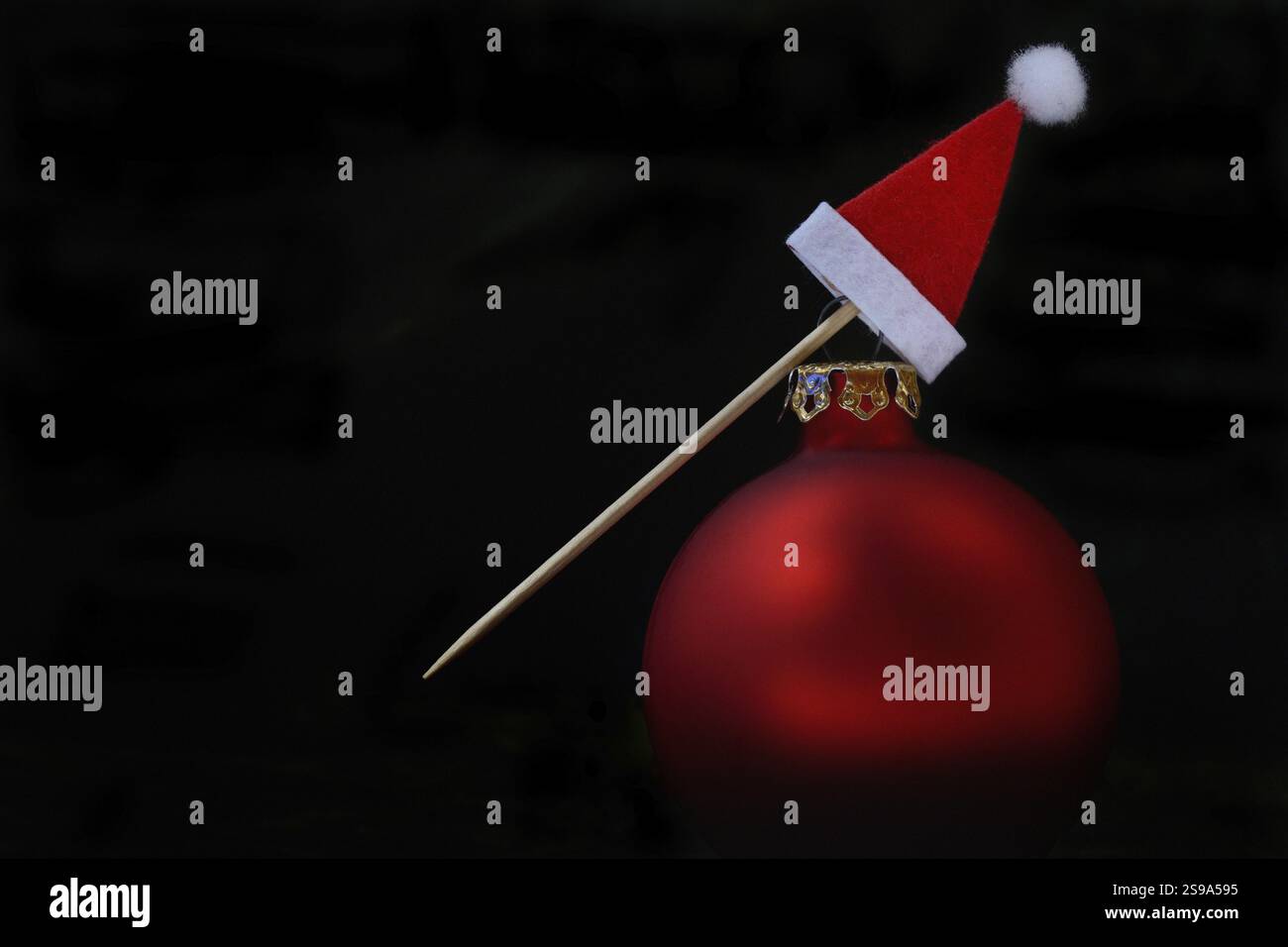 Rote Weihnachtskugel und Weihnachtsmütze auf einem Zahnstocher Stockfoto