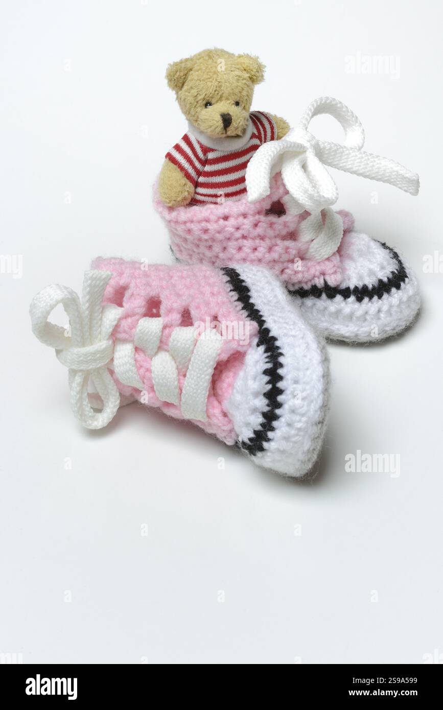 Babyschuhe und Teddybär, weißer Hintergrund Stockfoto