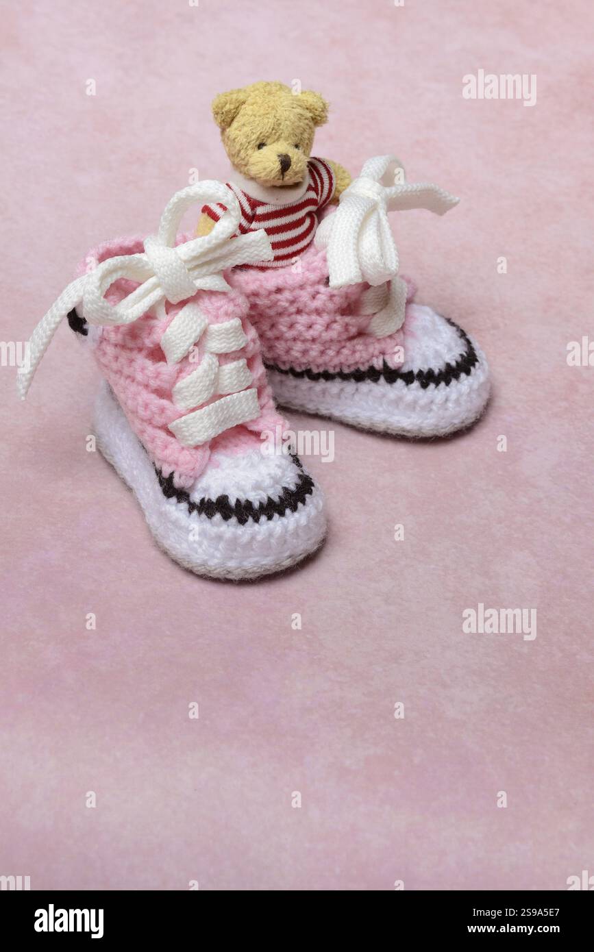 Babyschuhe und Teddybär mit rosa Hintergrund, handgefertigt Stockfoto