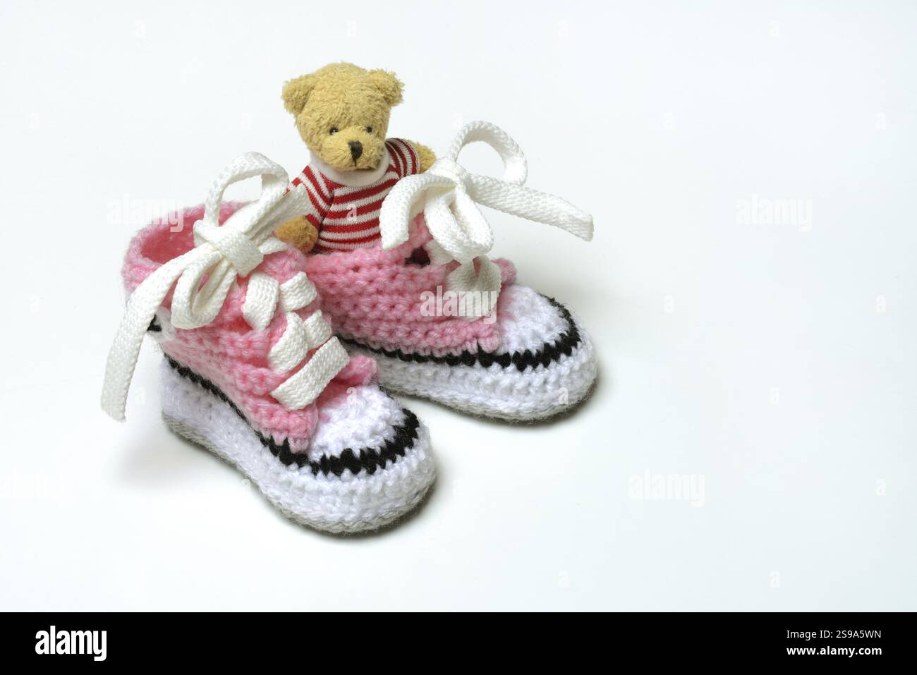 Babyschuhe und Teddybär, weißer Hintergrund Stockfoto