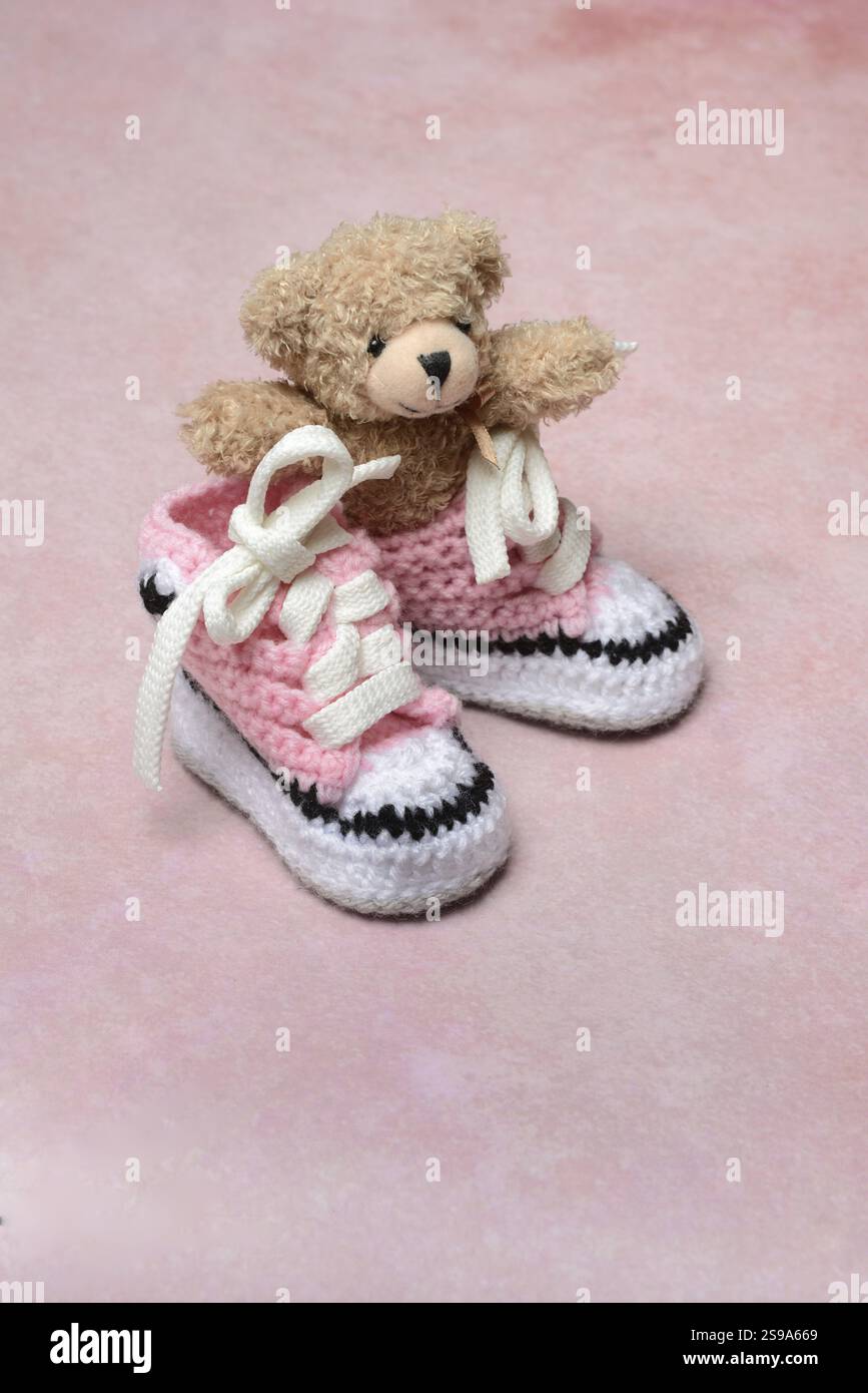 Babyschuhe und Teddybär mit rosa Hintergrund, handgefertigt Stockfoto