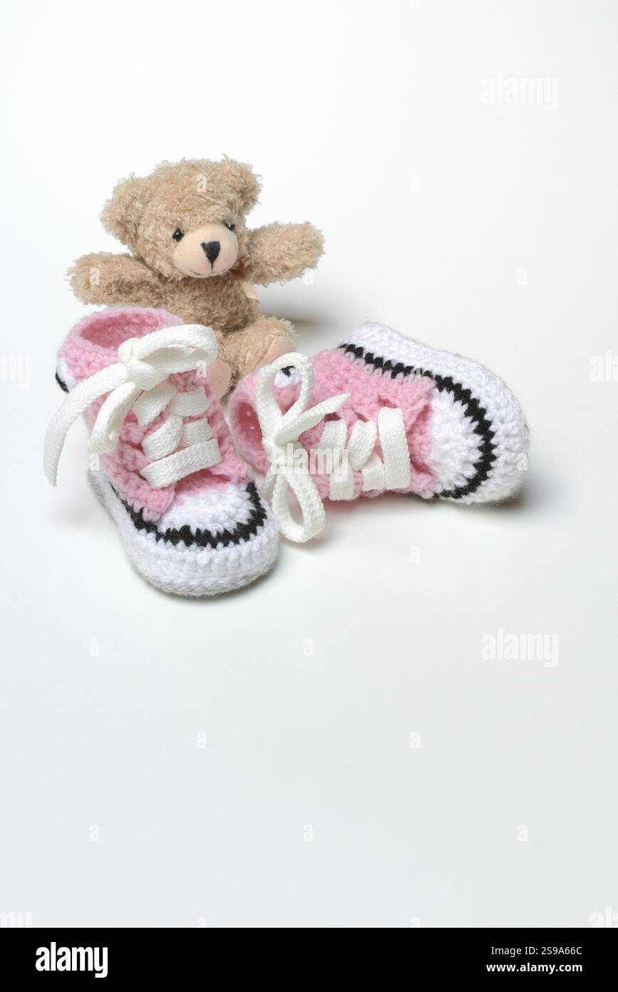 Babyschuhe und Teddybär, weißer Hintergrund Stockfoto