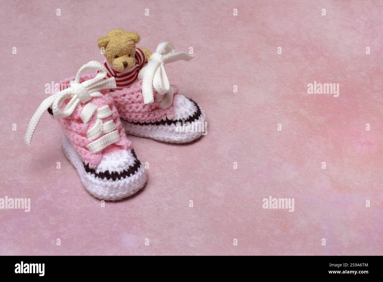 Babyschuhe und Teddybär mit rosa Hintergrund, handgefertigt Stockfoto