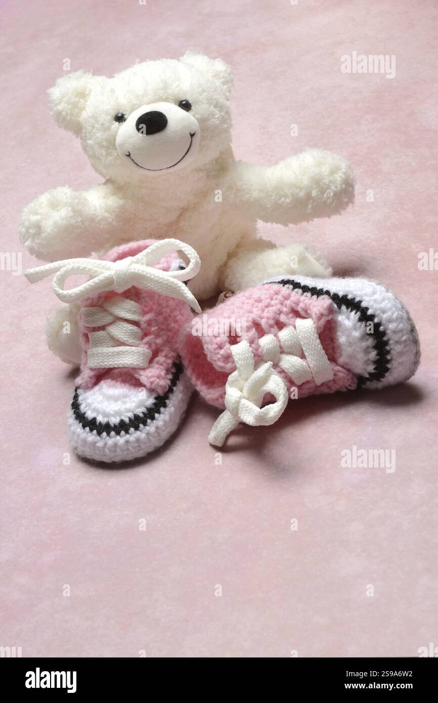 Pinkfarbene Babyschuhe mit Teddybär, rosa Hintergrund Stockfoto