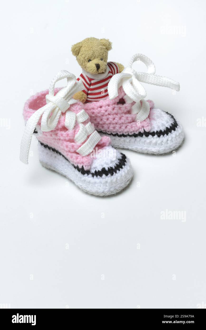 Babyschuhe und Teddybär, weißer Hintergrund Stockfoto